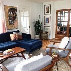 a living room filled with blue couches and wooden tables in front of two windows