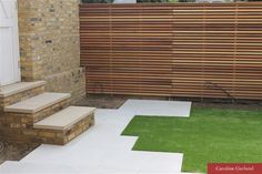 an outdoor area with grass and steps leading up to a brick fenced in area