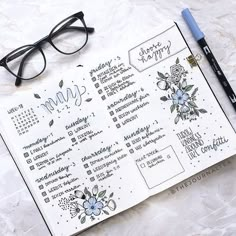 a planner with glasses on top of it next to a pen and eyeglasses