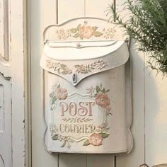 a white mailbox sitting on the side of a wall next to a potted plant