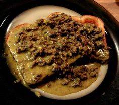 a plate topped with meat and gravy covered in sauce on top of bread