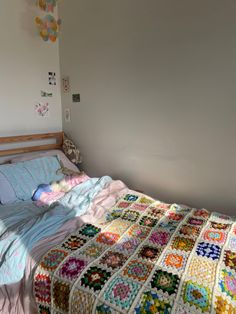 a bed with a quilt on top of it in a bedroom next to a wall