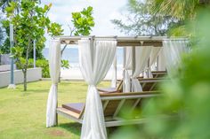 an outdoor area with white curtains and wooden benches