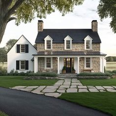 a white house with black shutters on the front and side windows is surrounded by green grass