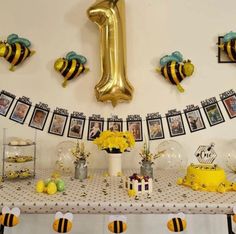 a table topped with pictures and balloons covered in honeybees next to a number one balloon