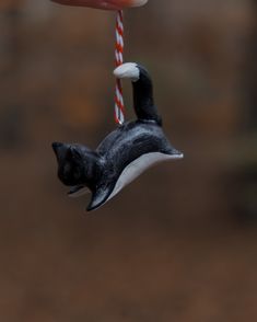 a black and white cat ornament hanging from a red and white striped cord