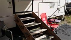 the stairs lead up to an rv that is parked next to some chairs and tables