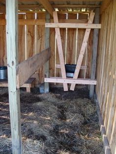 the inside of a wooden shed with hay and buckets in it's stall