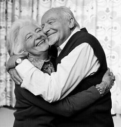 an older man and woman hugging each other