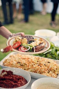 a person is serving food from a platter on a table with other plates and bowls