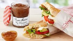 two sandwiches cut in half on a cutting board next to a jar of peanut butter and jelly