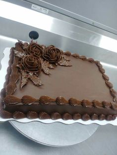 a chocolate cake sitting on top of a white plate covered in frosting and roses