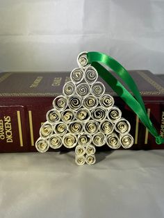 an origami christmas tree on top of a stack of books with a green ribbon