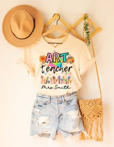 ABOUT OUR Personalized Art Teacher Shirt: PRODUCTION TIME: 1-3 days (Usually 2 days) SHIPPING TIME: 2-5 days (Usually 3 days) PRODUCT DESCRIPTION: Bella Canvas Unisex T-shirt Super soft cotton and excellent quality print makes. 100% Soft cotton (fibre content may vary for different colors) Light fabric (4.2 oz/yd² (142 g/m Runs true to size Our Relaxed Fit Tee (Bella + Canvas style 3001) is a unisex style that runs a touch small for men, and about a half a size large for women. It's a relaxed fit and is soft and cozy. * For T-shirt Sizes Please refer to the Listing Image. CARE INSTRUCTION: Machine wash: warm (max 40C or 105F); Non-chlorine: bleach as needed; Tumble dry: low heat; Iron, steam or dry: medium heat; Do not dryclean PRINTING METHOD: DTG printing method is used for these shirts. Cheap Custom Artwork T-shirt With Relaxed Fit, Artsy Cotton T-shirt With Custom Print, Artistic Short Sleeve Top With Artwork, Artsy Short Sleeve Tops With Artwork, Cotton Artwork T-shirt With Short Sleeves, Artistic Multicolor Cotton Shirt, Graphic Cotton Tee With Artwork, Artistic Relaxed Fit Shirt With Letter Print, Artistic Multicolor Letter Print T-shirt