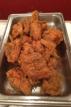 fried chicken is in a metal pan on the stove