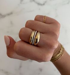 a woman's hand with two gold rings on her left and one in the middle