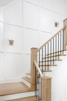 a staircase with white walls and wood handrails