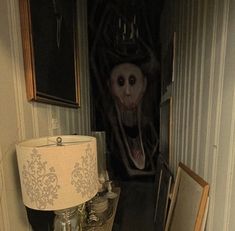 a creepy looking room with a lamp and pictures on the wall