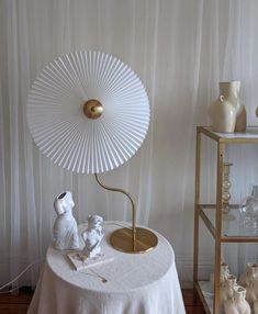 a white table topped with a gold lamp and figurines on top of it