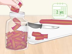 a jar filled with red hot dogs next to a person's hand holding a knife