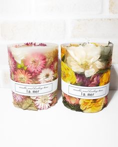 two candles with flowers on them sitting next to each other