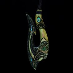 an artistically designed pendant hangs on a black background in the shape of a fish