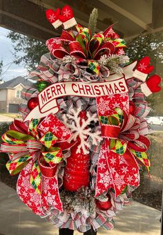 a red and white christmas wreath on the front door