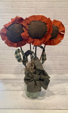 three sunflowers in a glass vase with burlocks and plaid ribbon tied around them