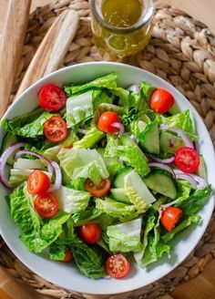 a salad with tomatoes, cucumbers and lettuce in a white bowl