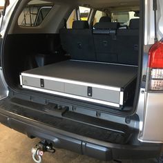 the back end of a silver car with its trunk open and two speakers in it