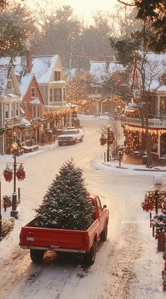 a red truck carrying a christmas tree down a snowy street