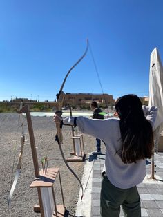 a woman is aiming an arrow at something in the air while others look on from behind her