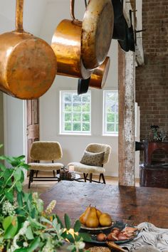 pots and pans hanging from the ceiling in a living room with wood flooring