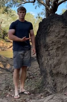 a man standing next to a large rock