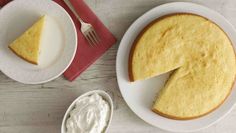 a piece of cheesecake on a plate with a fork and bowl of whipped cream