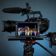 a video camera on a tripod with a city skyline in the background