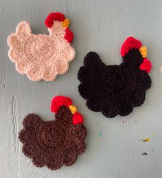 three crocheted roosters sitting next to each other on a white table top