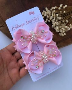 two pink bows with pearls on them are being held up by someone's hand