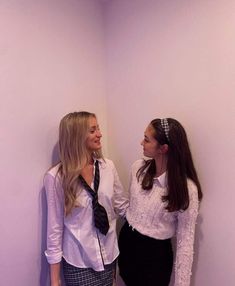 two young women standing next to each other in a room with purple walls and white walls