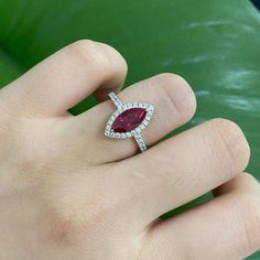 a woman's hand holding a ring with a large red stone in the middle