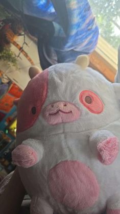 a white stuffed animal with pink and red eyes sitting on top of a wooden table