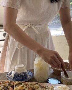 a woman in a white dress is cutting up some food on a wooden table with utensils