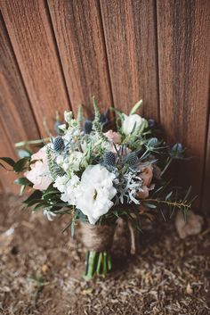 a bridal bouquet sitting on the ground next to a wooden wall