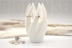 a white vase with two rings on it and some fur in the back ground next to it