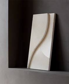 a white sculpture sitting on top of a shelf next to a black wall in a room