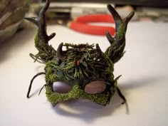 a close up of a mask made out of moss with antlers and leaves on it