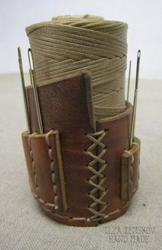 there is a brown leather cuff with two needles in the center and some yarn on top