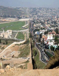 a view of a city from the top of a hill with cars driving down it