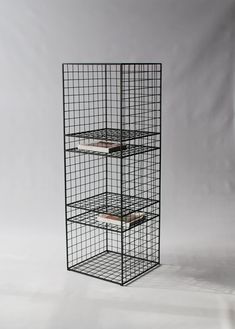 a black metal shelf with three shelves on each side and two books in the middle