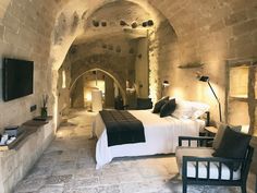 a bedroom with stone walls and an arched ceiling